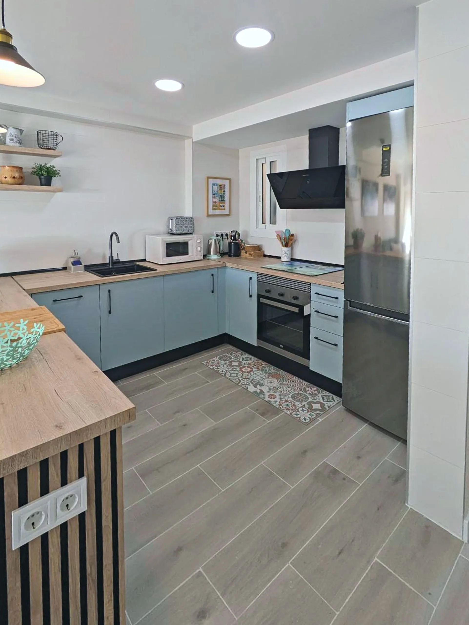 Cocina con horno, frigorífico y barra de madera
